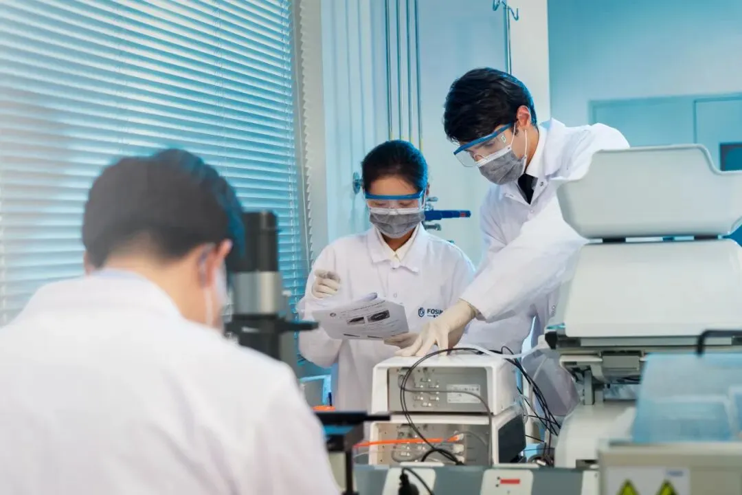 Researchers at a Fosun Kairos cell therapy laboratory beside cell processing equipment