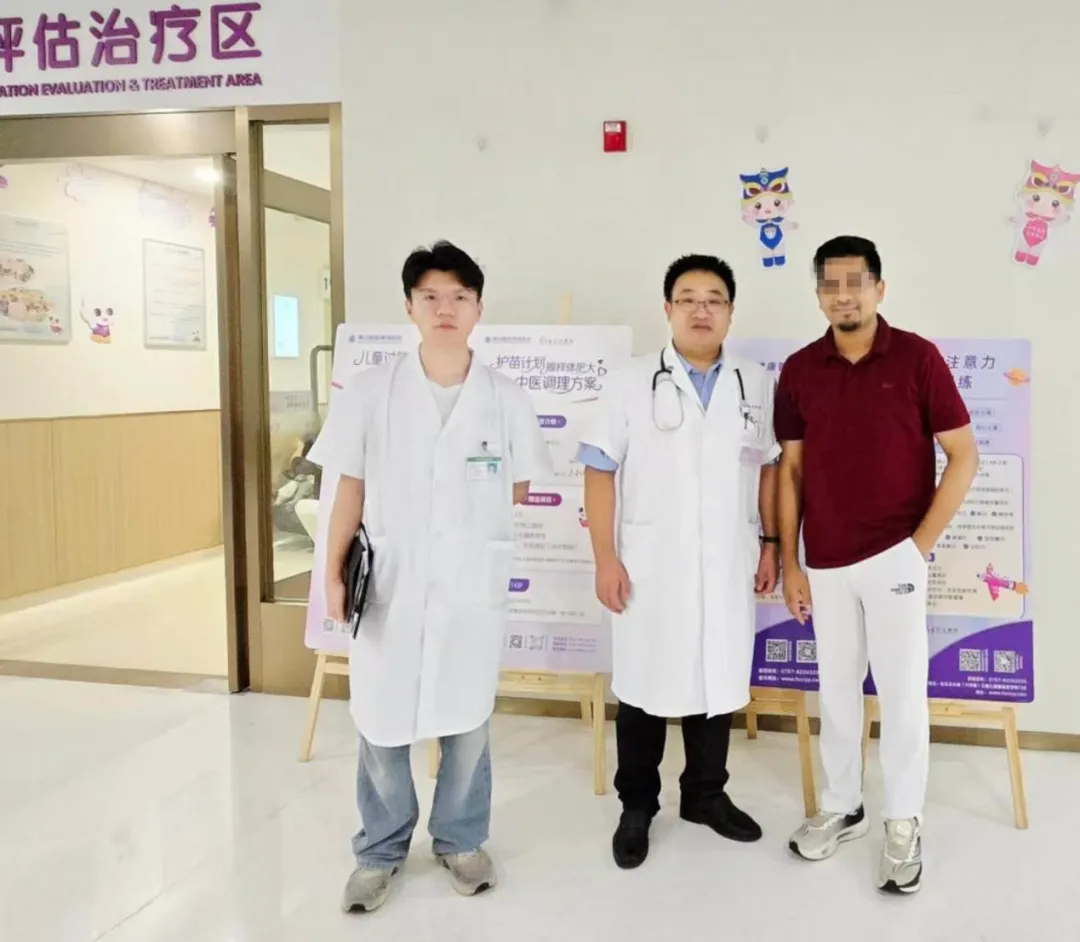 Dr. Liang Fujian of Foshan Chancheng Hospital standing with the father of a young Bangladeshi patient and a colleague in the hospital lobby